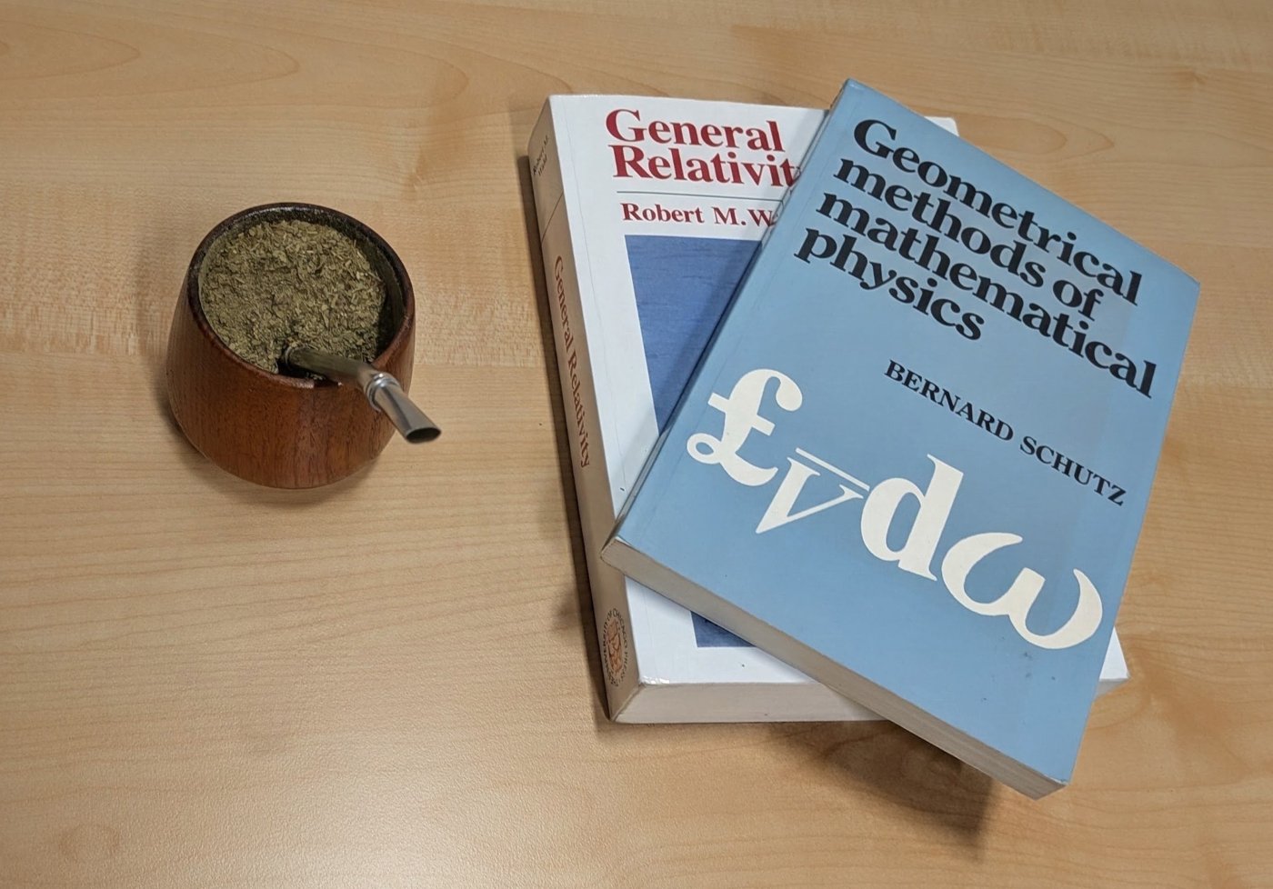 Mate and books on general relativity and mathematical physics on a desk